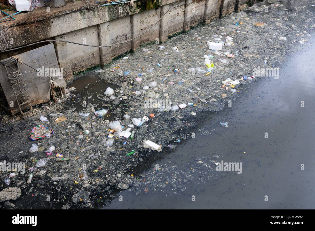 Dirty canal with plastic bottle and other garbage Stock Photo