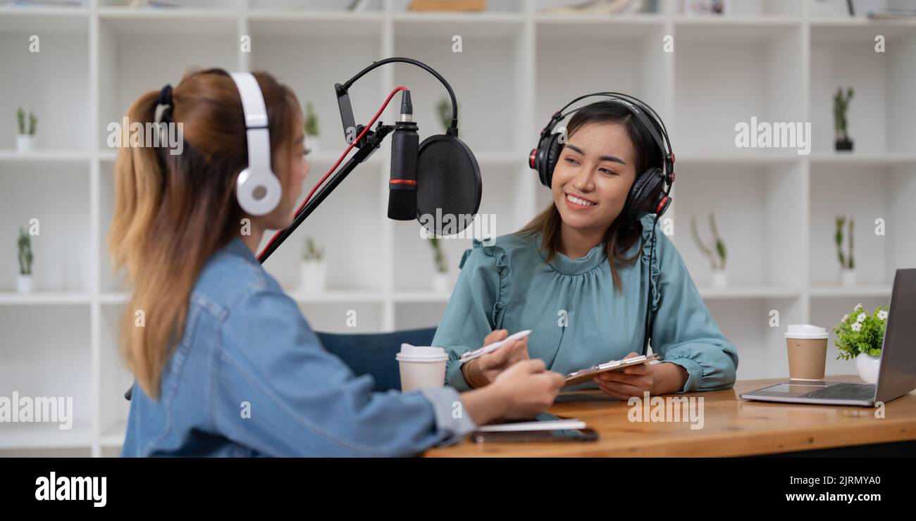 Female host recording radio podcast interview with guest at home office Stock Photo