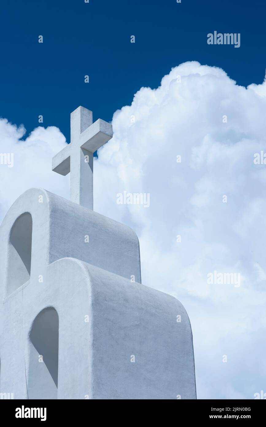 Church roof with white cross against blue sky and white clouds, Playa del Carmen, Mexico, vertical shot. Stock Photo