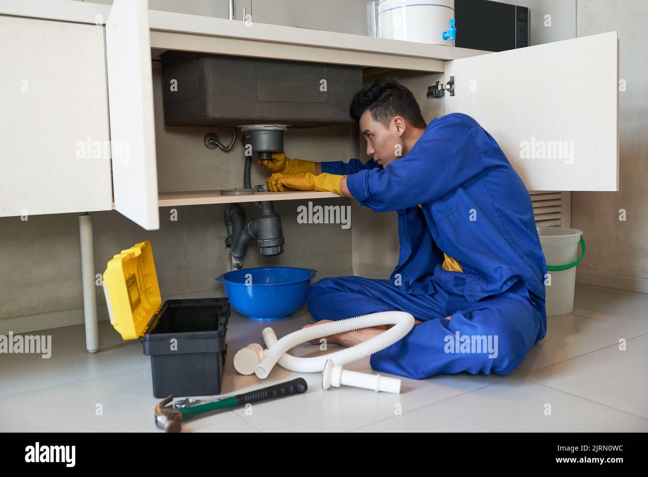 Young Vietnamese plumber checking drain in kitchen Stock Photo Alamy