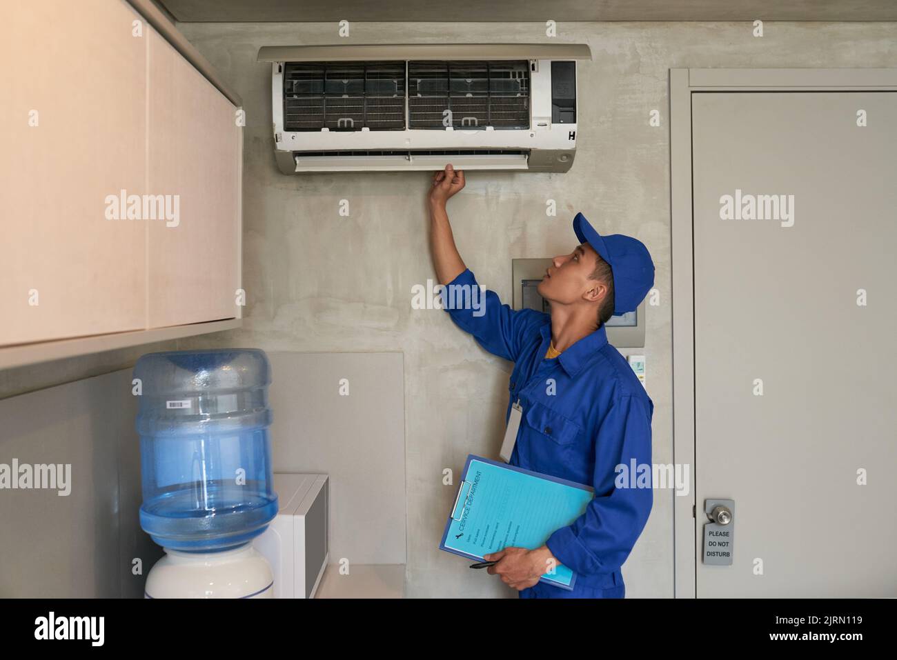 Young Asian technician checking conditioner in kitchen Stock Photo