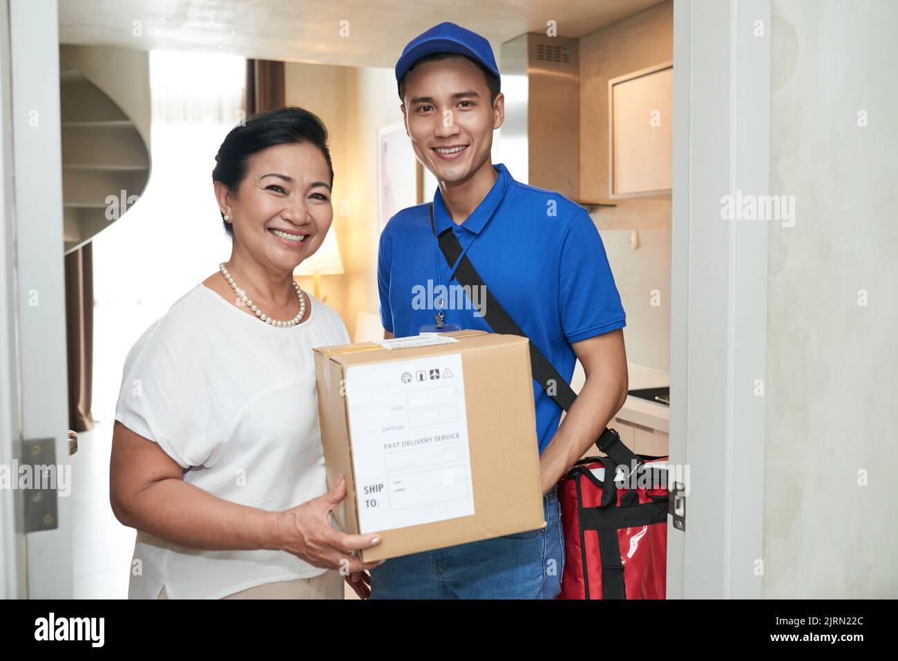 Happy senior woman and courier holding big box Stock Photo