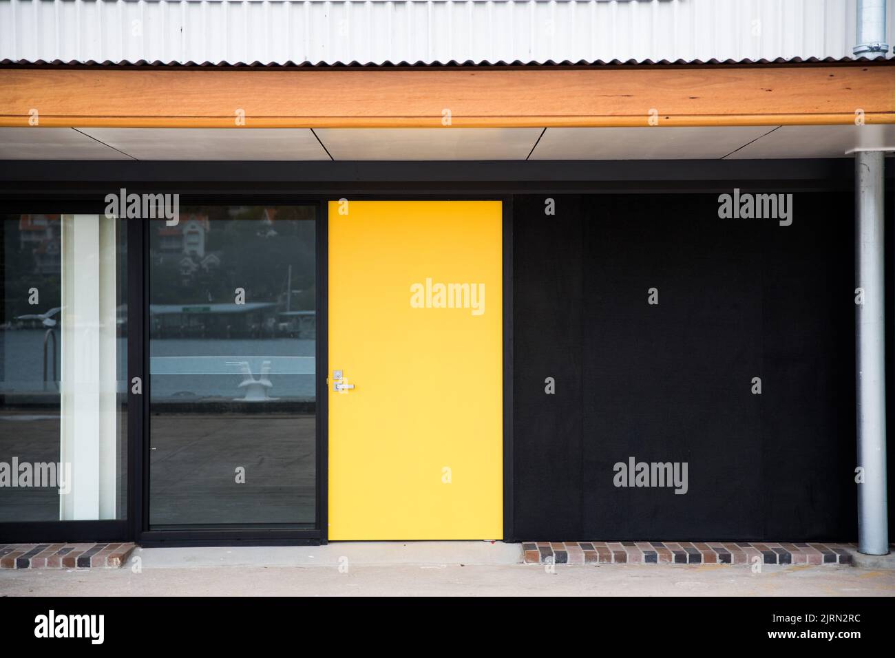 A front view of a yellow door of a modern house with the pool reflected