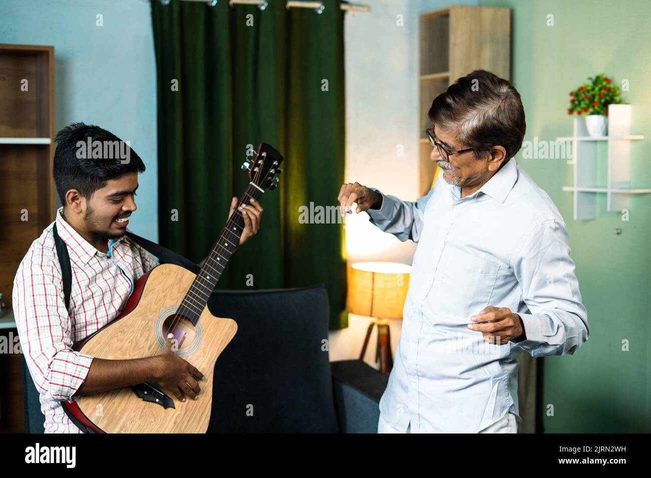 focus on old man, Happy father with son dancing by playing guitar at home - concept of leisure retirement lifestyles, family bonding and freedom Stock Photo