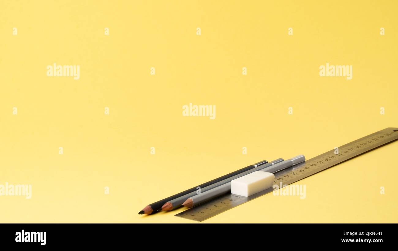Simple pencils, ruler and eraser on a yellow background Stock Photo
