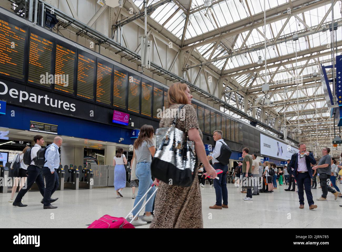 Low angle view of the concourse of Waterloo main line station with waiting passengers looking at the departure board, London England UK Stock Photo