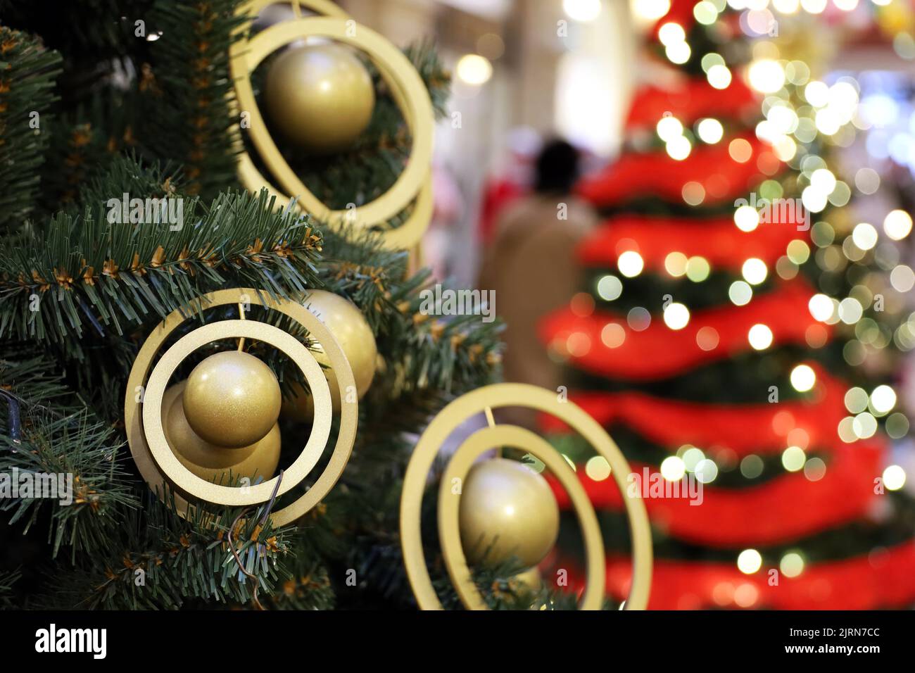 Christmas tree with golden toys in a shopping mall on background of blurred festive lights. New Year decorations, winter holidays and sale Stock Photo