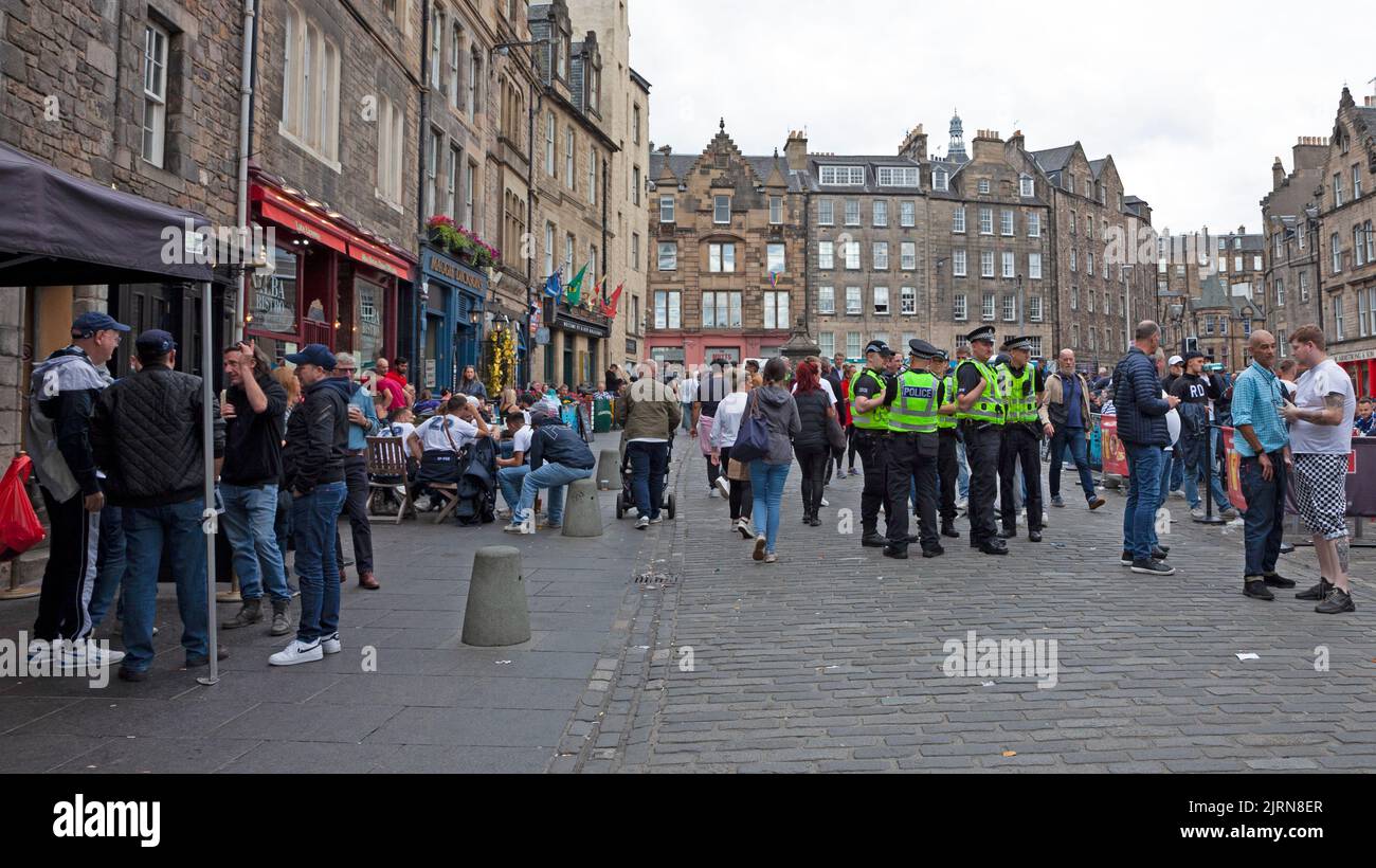 City centre Edinburgh, Scotland, UK. 25th August 2022. Cloudy but mild 19 degrees centigrade for the FC Zurich fans who gathered surrounded by Police Officers in the untidy Grassmarket to peacefully socialise before this evening's game with Heart of Midlothian. Also, smaller crowds in the Royal Mile for street performers. Pictured: Police Officers in a huddle making their presence obvious to the peaceful FC Zurich fans who are having a drink. Credit: ArchWhite/alamy live news. Stock Photo