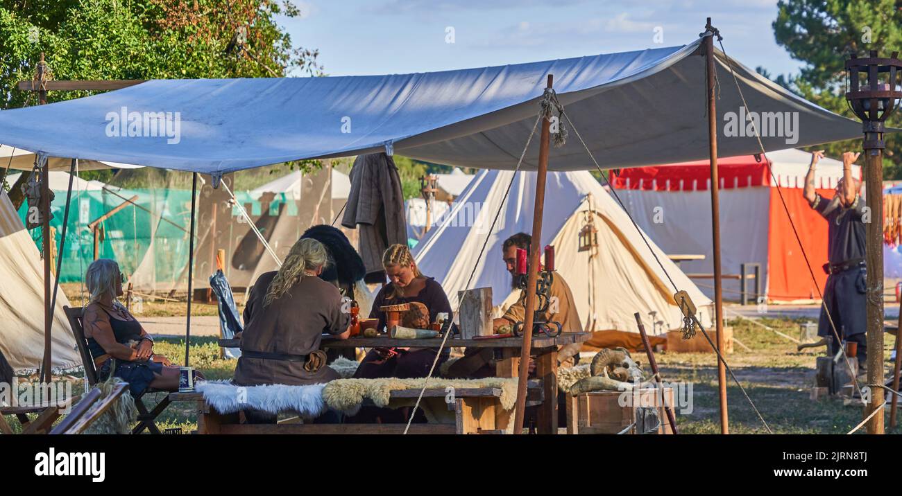 Gifhorn, Germany, August 12, 2022 People in medieval costumes take a meal together under a