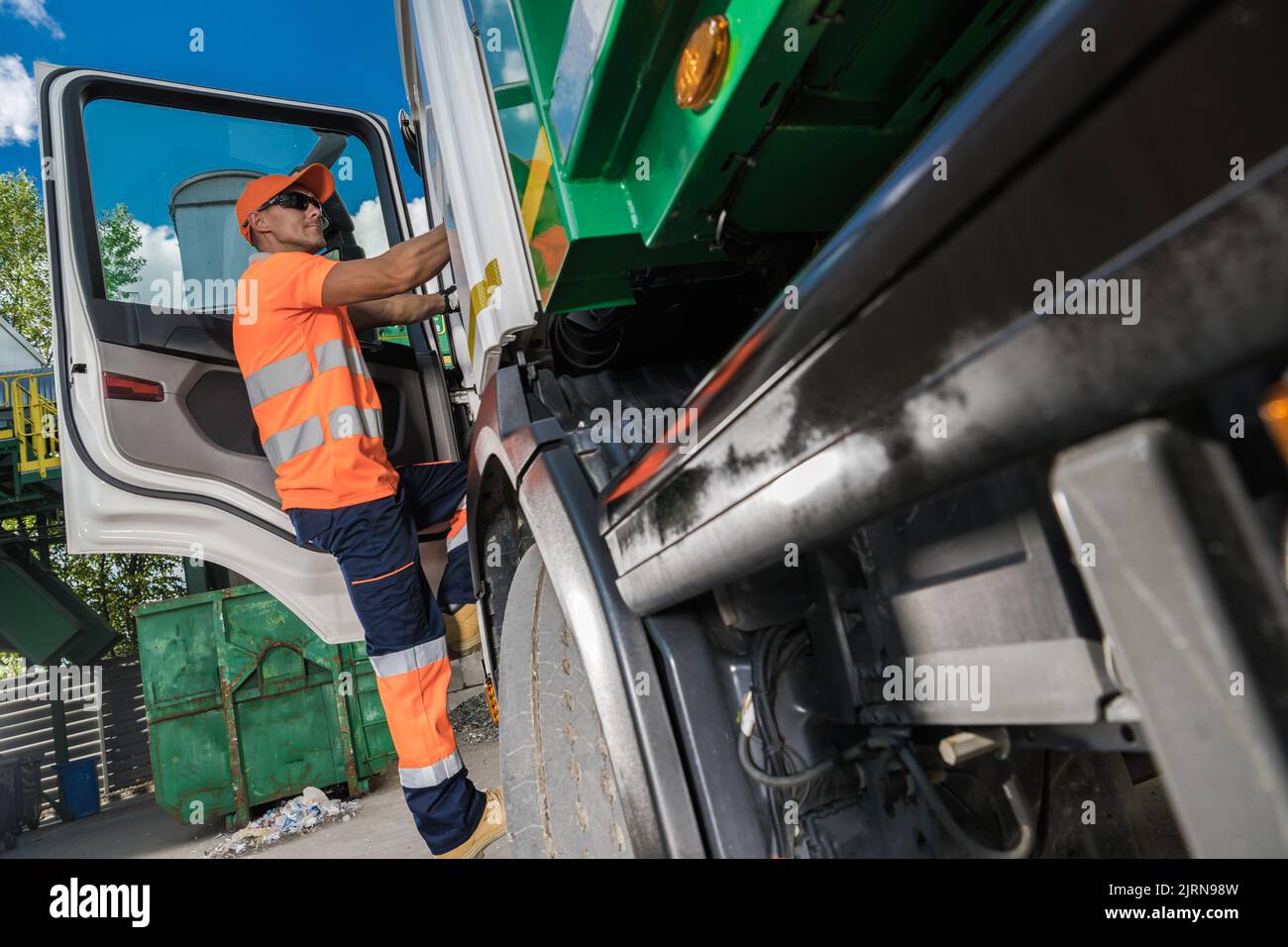 Waste Management Theme. Caucasian Garbage Truck Driver in His 40s Collecting City Garbage and Delivering to a Sorting Facility Stock Photo