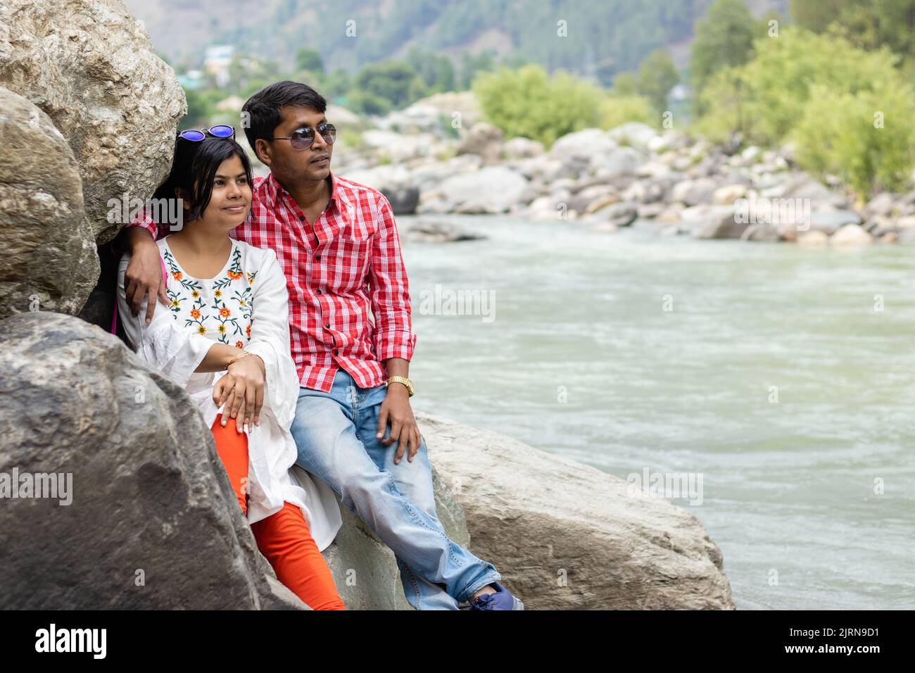 An Indian couple sitting on rocks beside a river Stock Photo - Alamy