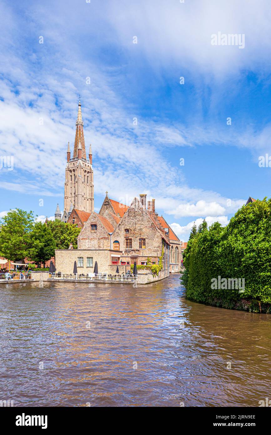The spire of the Church of Our Lady (Onze-Lieve-Vrouwekerk) overlooking St Johns Hospital (Sint-Janshospitaal) and old houses beside the canal in Brug Stock Photo