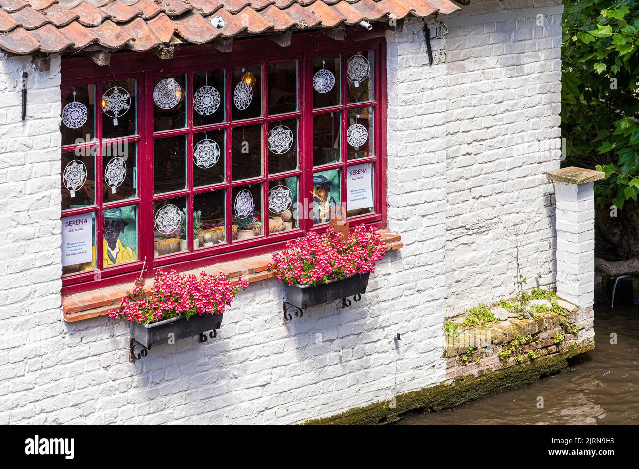 Flowers in troughs outside a Belgian lace shop overlooking the canal in Bruges, Belgium Stock Photo
