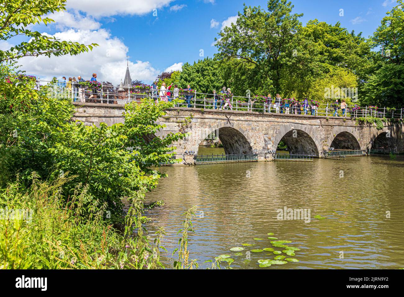 Tourists crossing the Minnewaterbrug (Lovers Bridge) over the Minnewater (Lake of love) in Bruges, Belgium Stock Photo