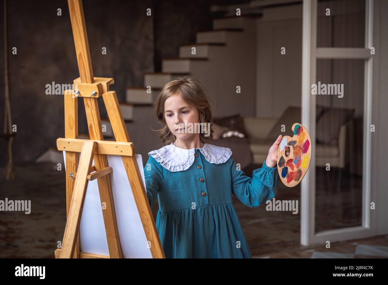 cute little girl draws behind an easel. dreaming Stock Photo Alamy