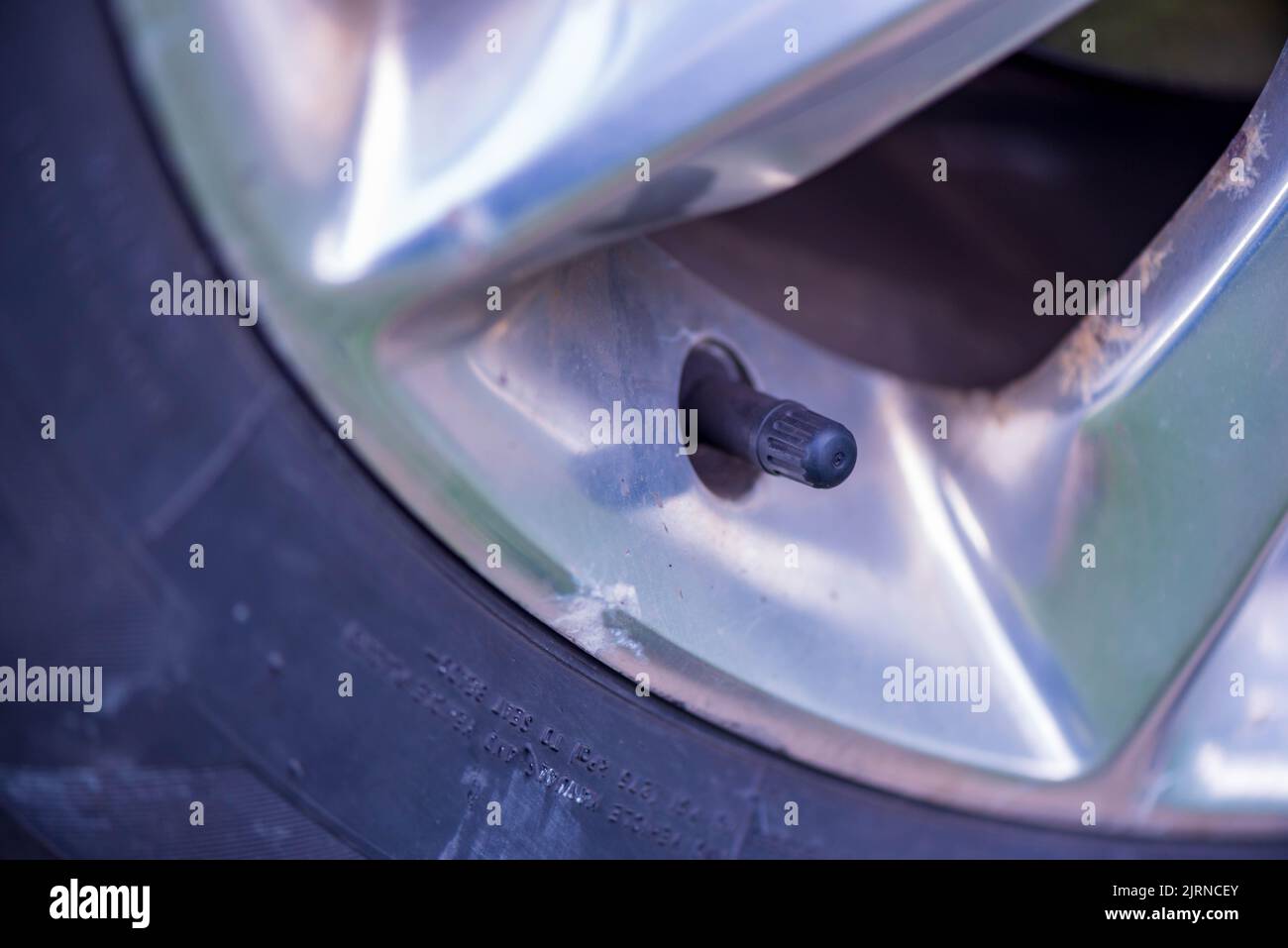 Tire air pressure valve with cap and car wheel with oxidation Stock