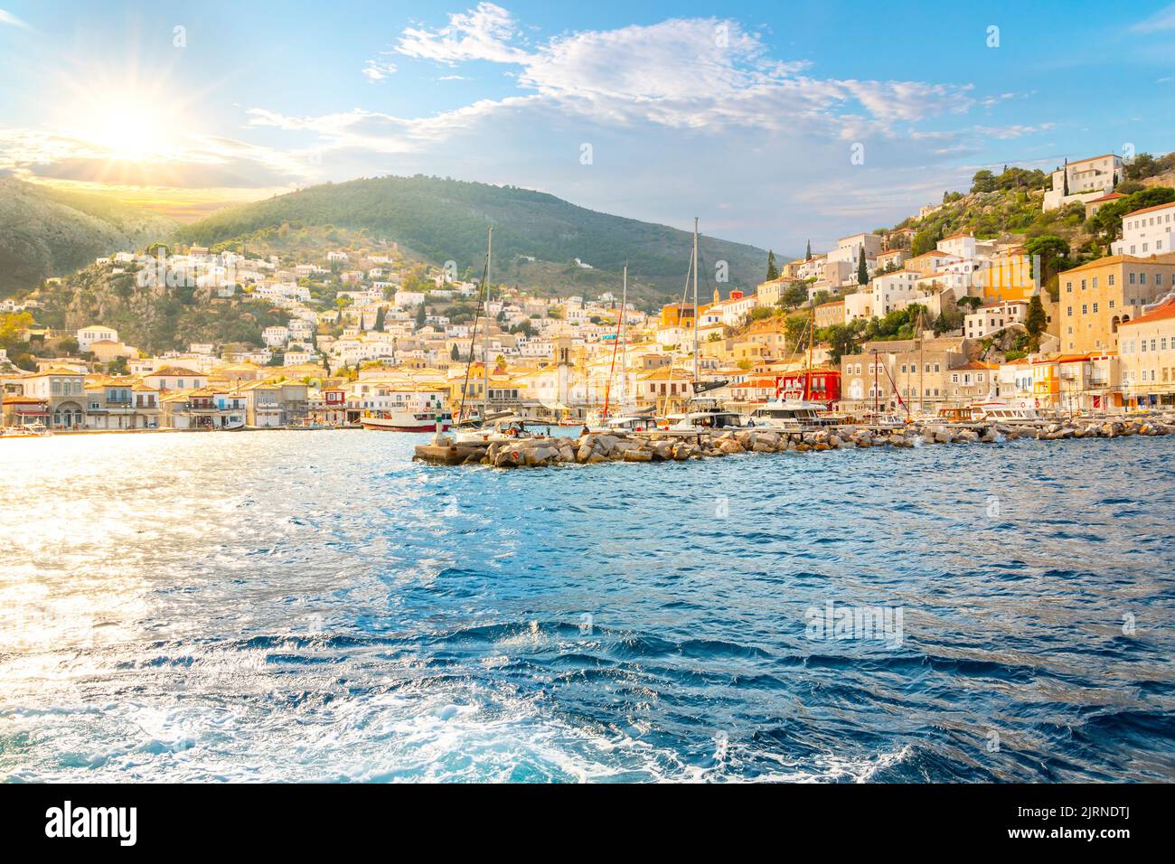 The picturesque and colorful village of Hydra on the Saronic island of Hydra, Greece, as the sun sets in the Aegean Sea. Stock Photo
