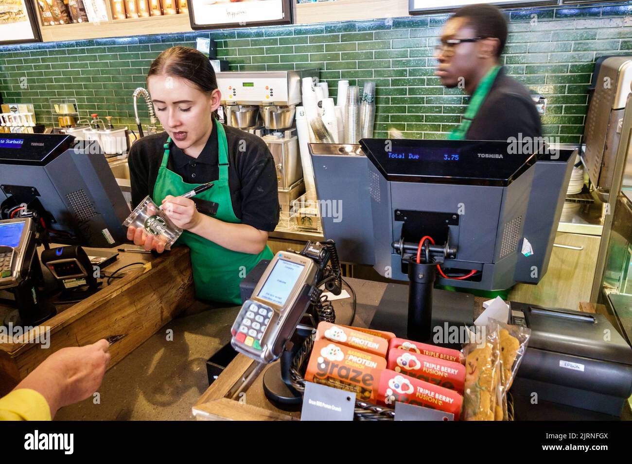 London England,UK Starbucks Coffee inside interior counter,Black man woman writing order on cup barista baristas workers,employees Stock Photo