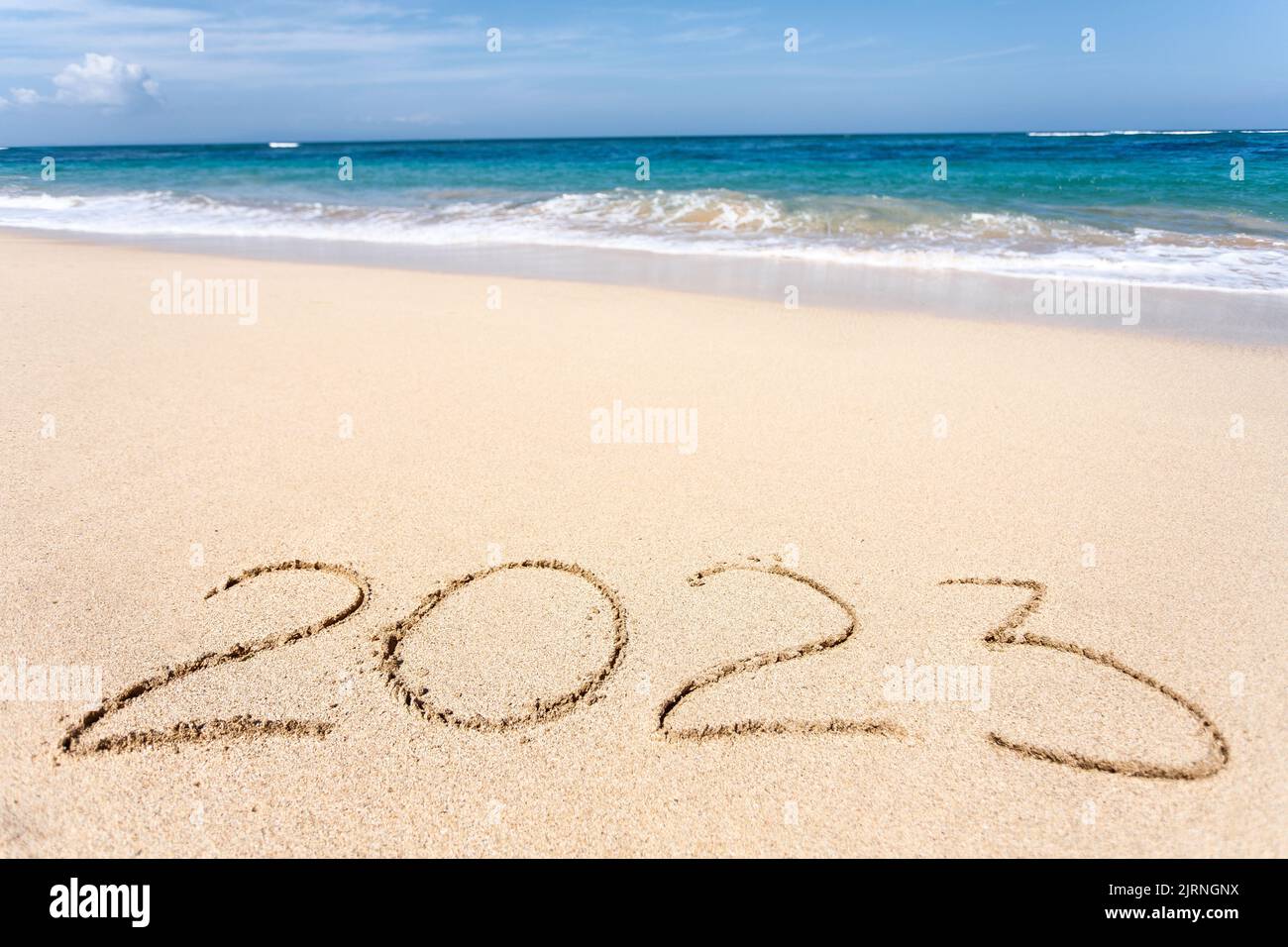 Happy New Year 2023, lettering on the beach with wave Stock Photo