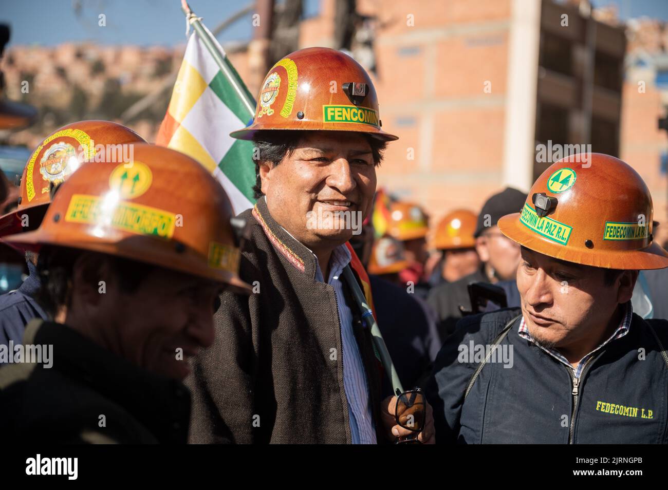 La Paz, Bolivia. 25th Aug, 2022. Evo Morales (m.), former president of  Bolivia, wears a helmet with the name of the mining association Fencomin  during a rally in support of the government. "