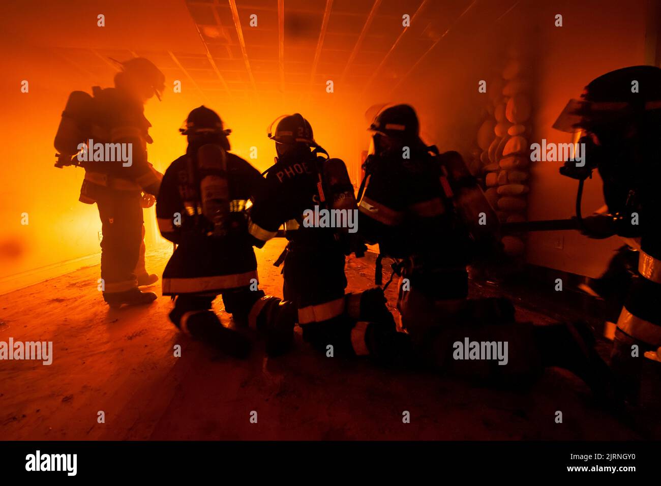 A senior Sag Harbor firefighter gives instruction to junior firefighters on how to attack a fire inside a building as members of the Sag Harbor Fire D Stock Photo