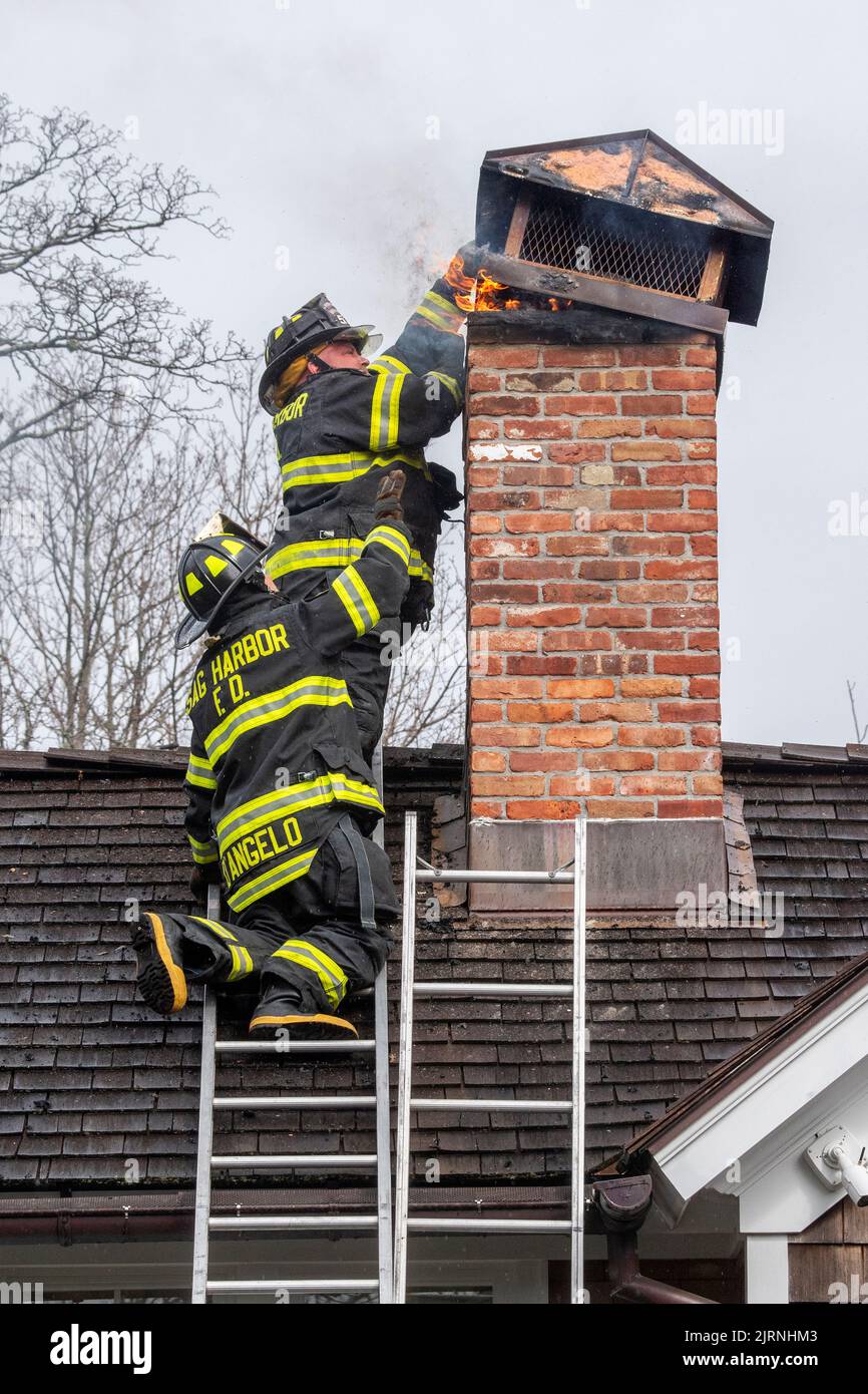 Firefighters remove a chimney cap off of the chimney after the Sag Harbor Fire Department responded to a chimney fire at 238 Madison Street on Monday Stock Photo