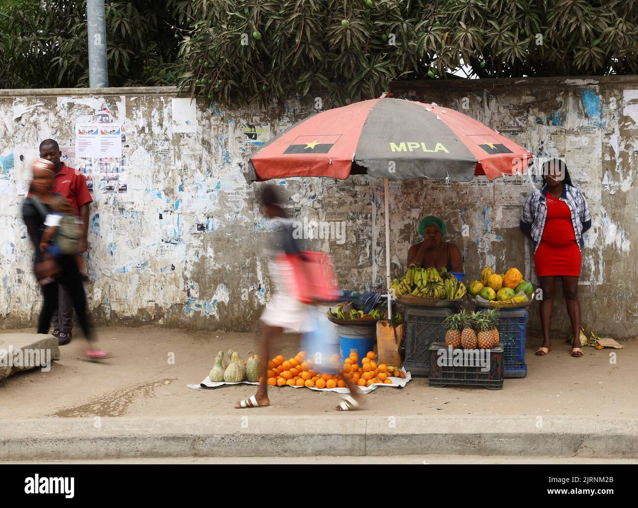 A woman selling fruits sits under an umbrella with a logo of people's Movement for the Liberation of Angola (MPLA)  as Angola's ruling party, which has been in power for nearly five decades, looked set to win a national election with a solid lead over the main opposition in Luanda, Angola,  August 25, 2022. REUTERS/Siphiwe Sibeko Stock Photo