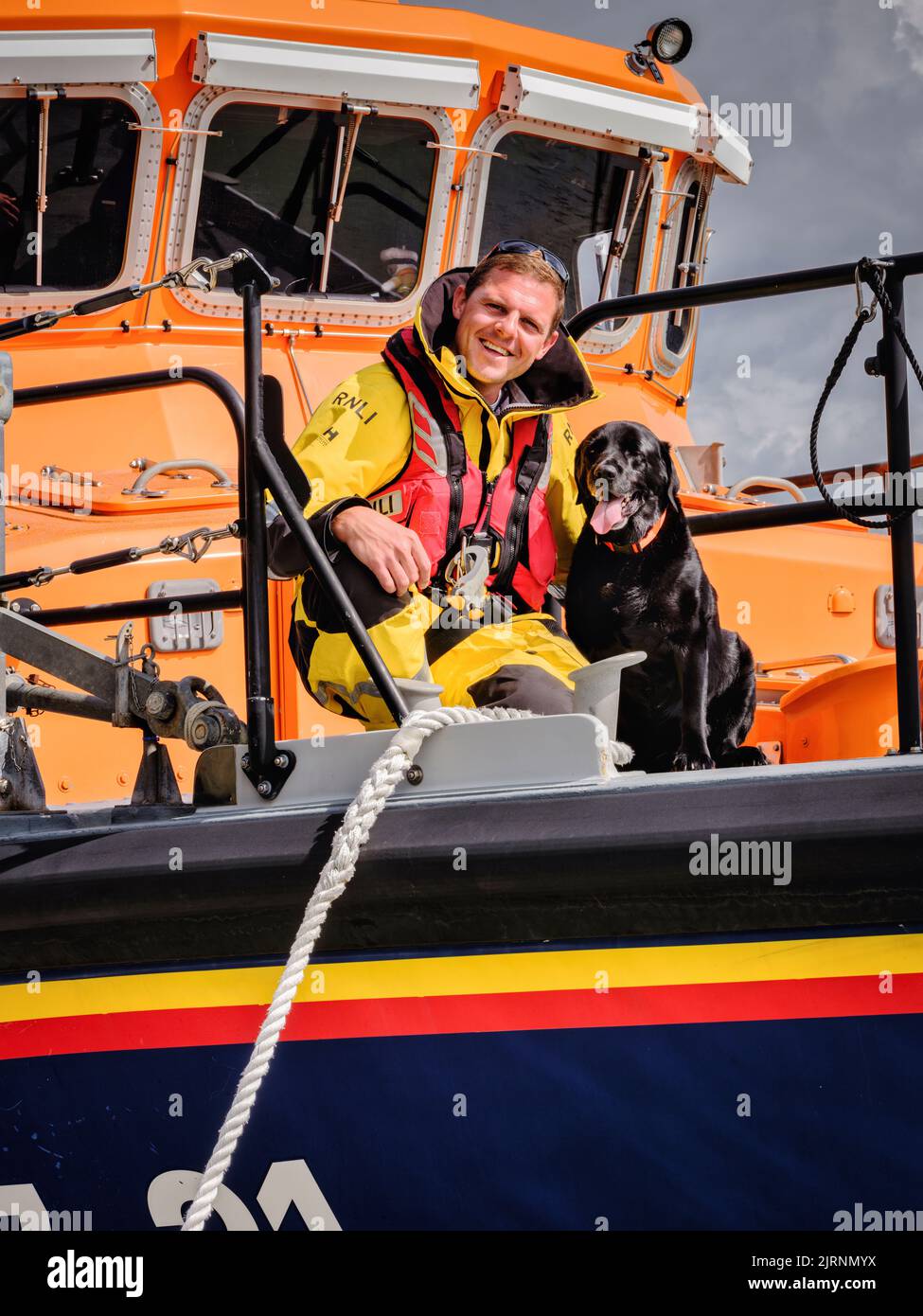 Editorial Use Only - Newhaven RNLI coxwain Lewis Arnold and his dog Oscar. Newhaven Lifeboat, East Sussex, UK. Picture by Jim Holden Stock Photo