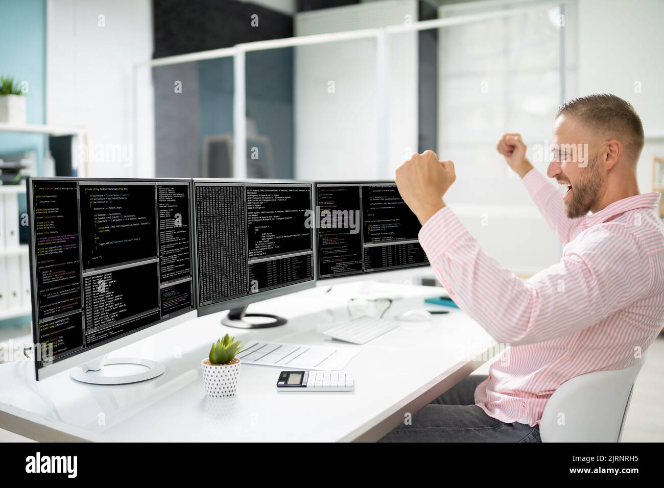 Excited Programmer Using Multiple Computer Screens. Engineer Celebrating Win Stock Photo