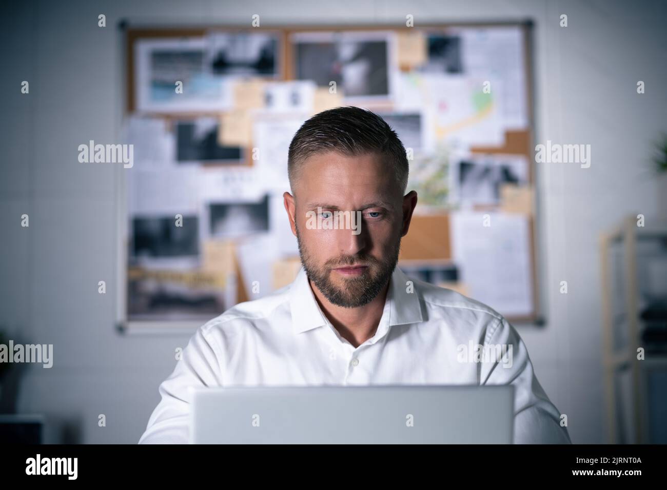 Private Detective Man Searching Online On Laptop Computer Stock Photo