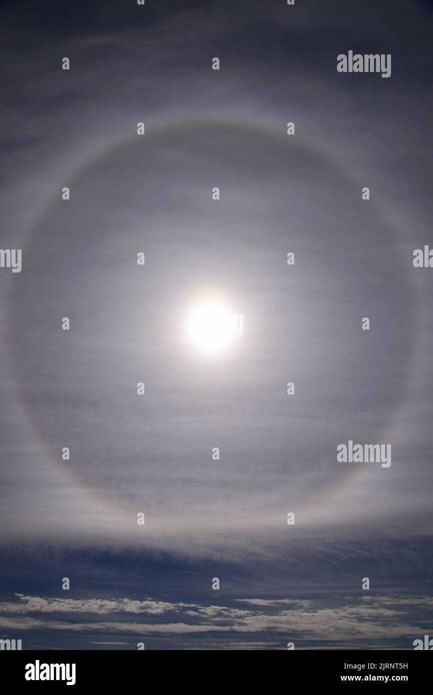 A vertical shot of a halo sun in the gray cloudy sky Stock Photo