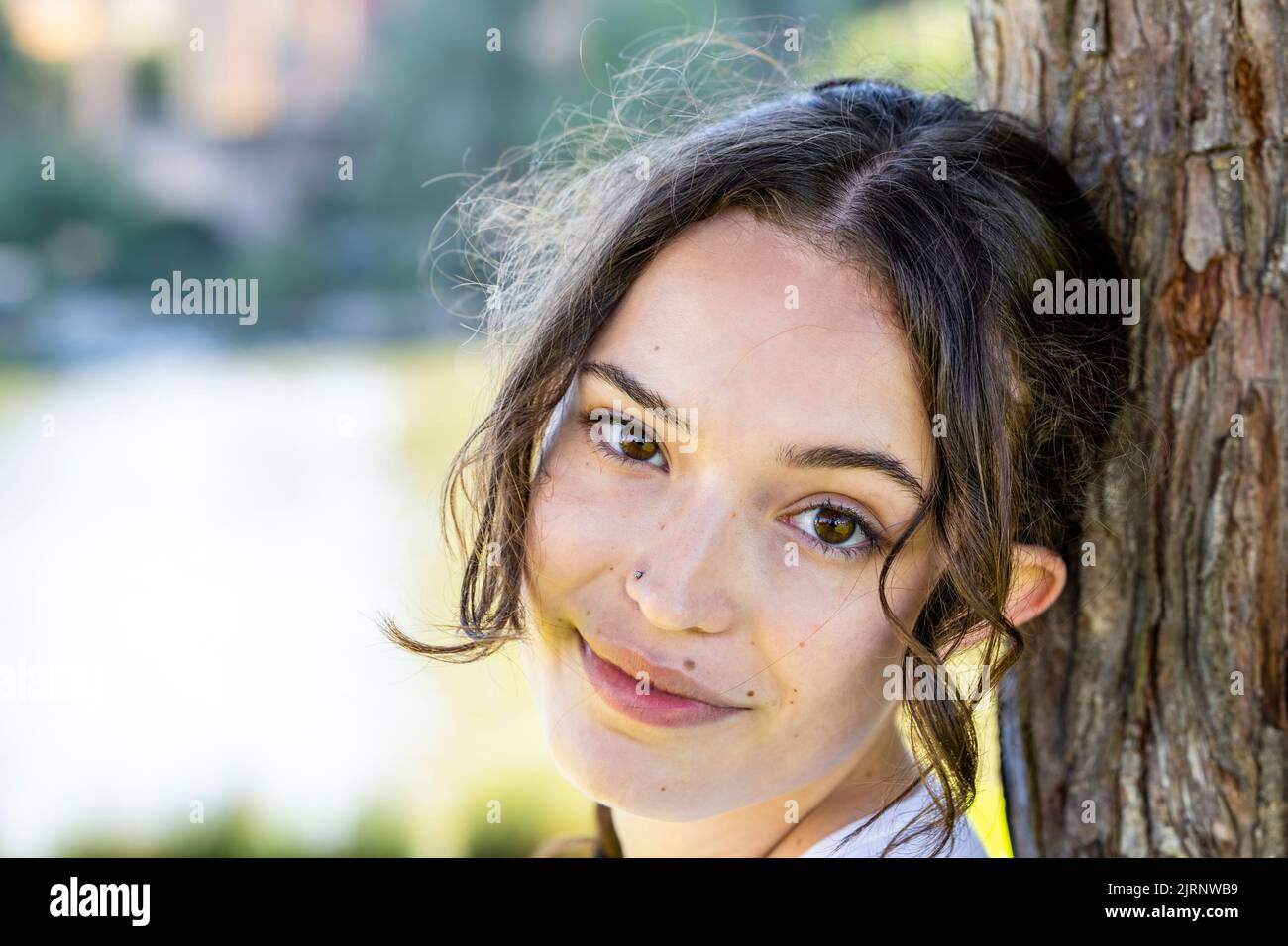 Close Up Portrait of a Young Woman Leaning on Tree with the Palace of Fine Arts in the Background Stock Photo