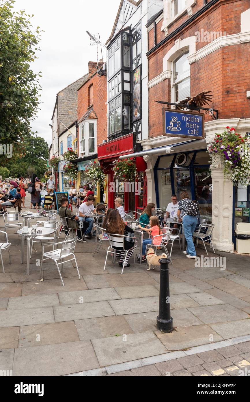 People sat at pavement cafes in Glastonbury Town centre, Market Place, Glastonbury, Somerset, England, UK Stock Photo