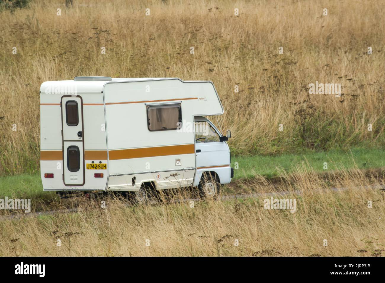 Vauxhall Bedford Rascal 1991 Nipper, 3 Berth, Overcab bed Campervan driving through parched summer countryside Stock Photo
