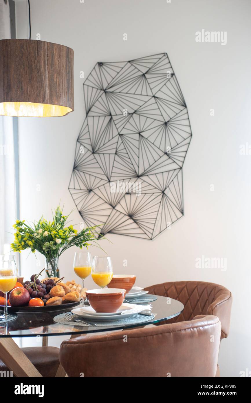 Round glass dining table with designer chairs upholstered in brown