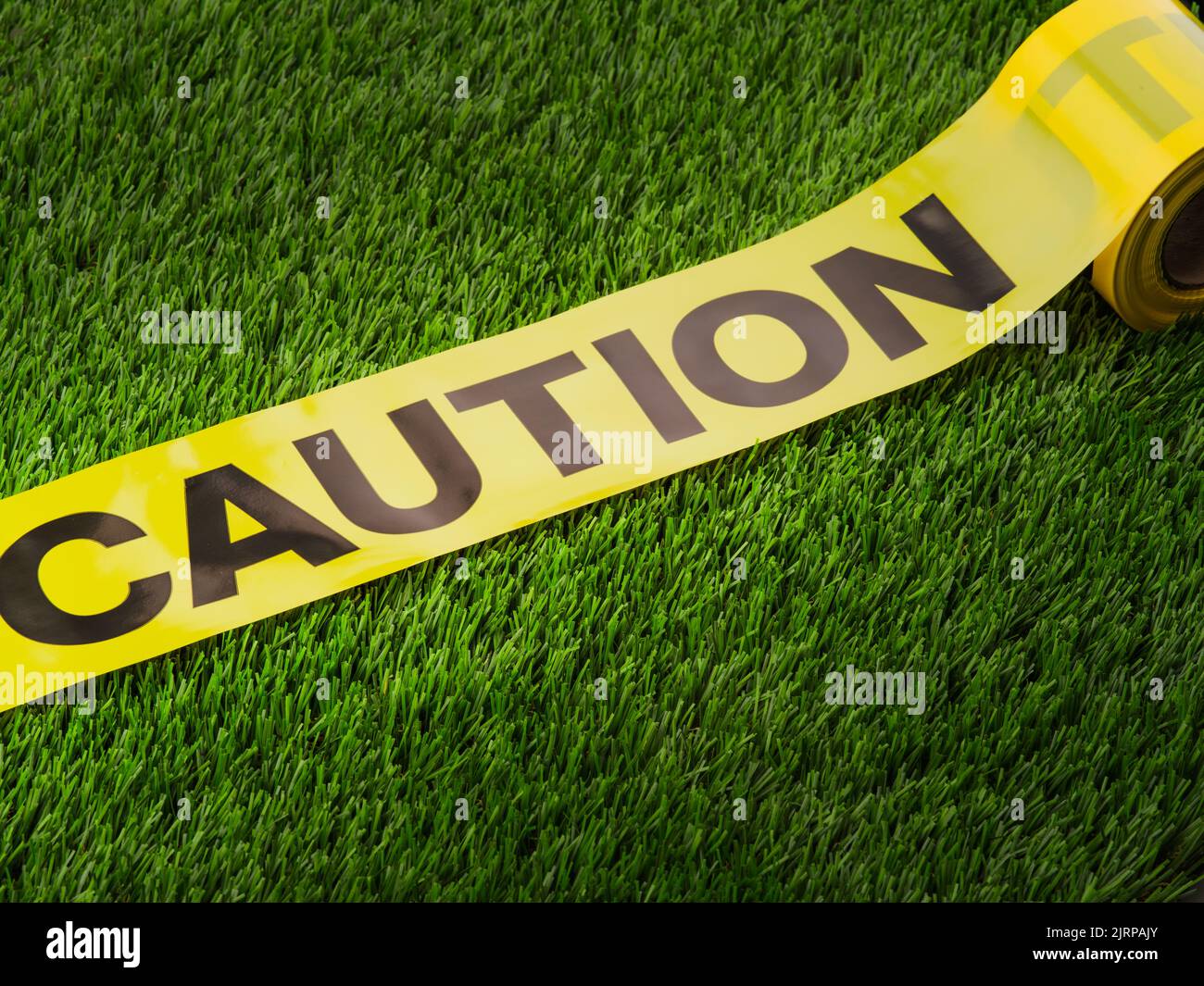 Caution black inscription on a yellow tape. Isolated on a green