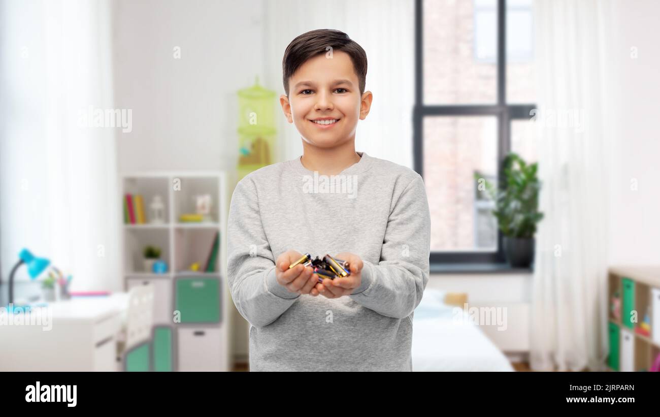 happy boy holding pile of batteries at home Stock Photo - Alamy