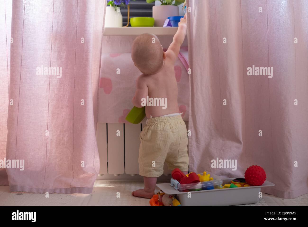 Caucasian baby playing with toys scattering them aroung. Messy room. Top view Stock Photo