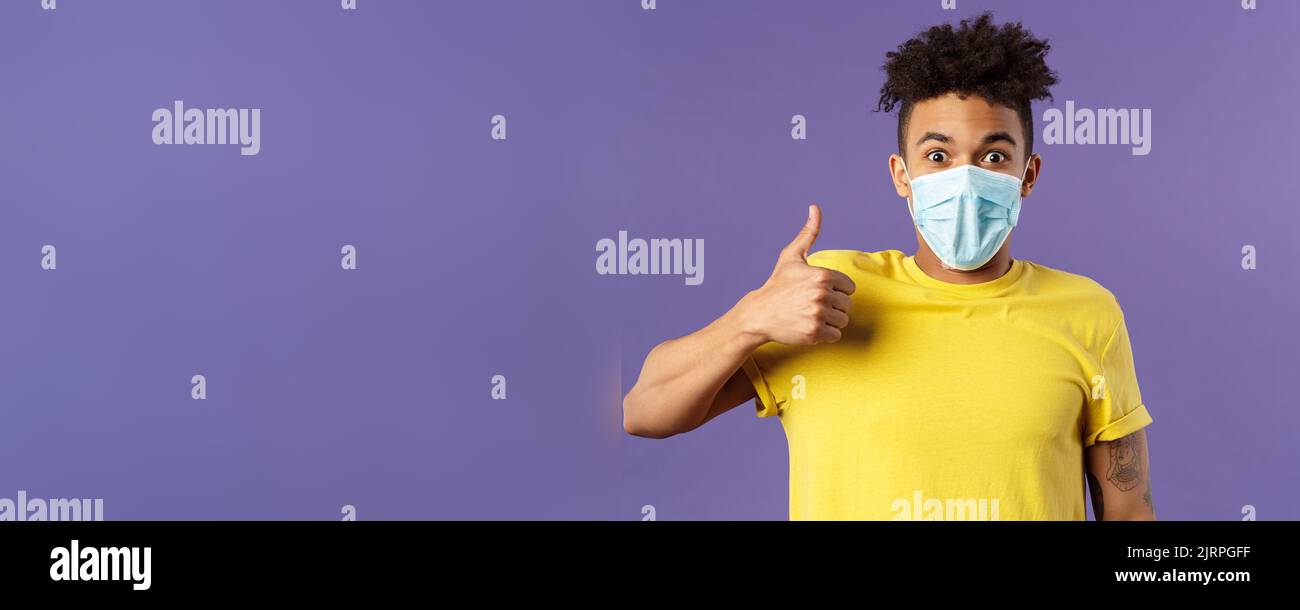 Covid19, healtcare and medicine concept. Excited young hispanic man in facial mask taking care of health, avoid public places, stay home and encourage Stock Photo