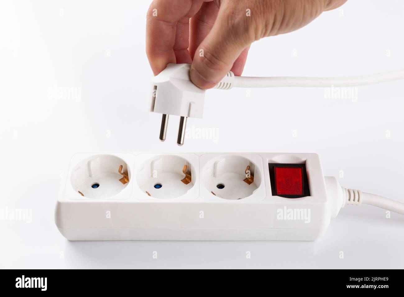 anonymous hand connects a plug to the mains. Electricity efficiency and rising energy costs Stock Photo