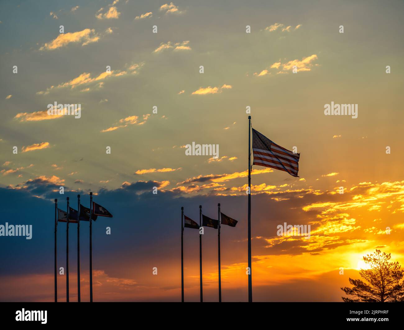 American Flag and several State Flags in silhouette against a cloudy sunrise sky. Stock Photo