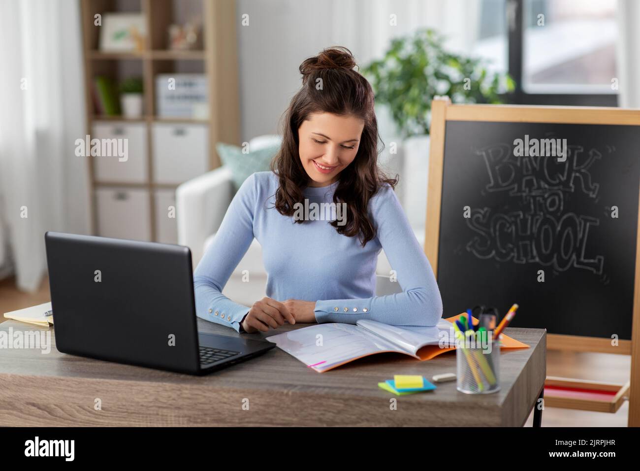 teacher with laptop and notebook working from home Stock Photo