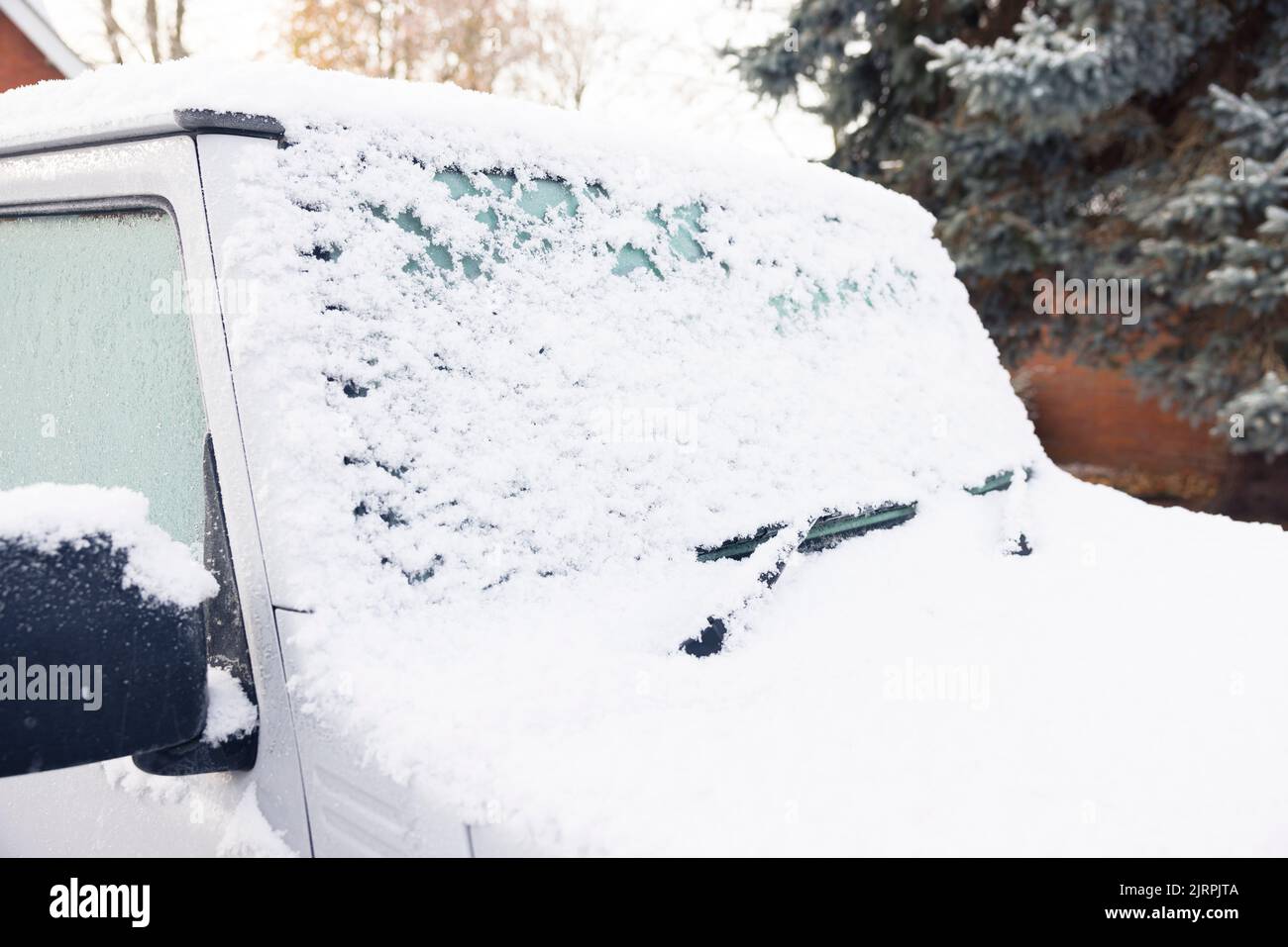 Snow and ice covering a car windscreen or windshield, parked on a driveway outside a house, UK Stock Photo