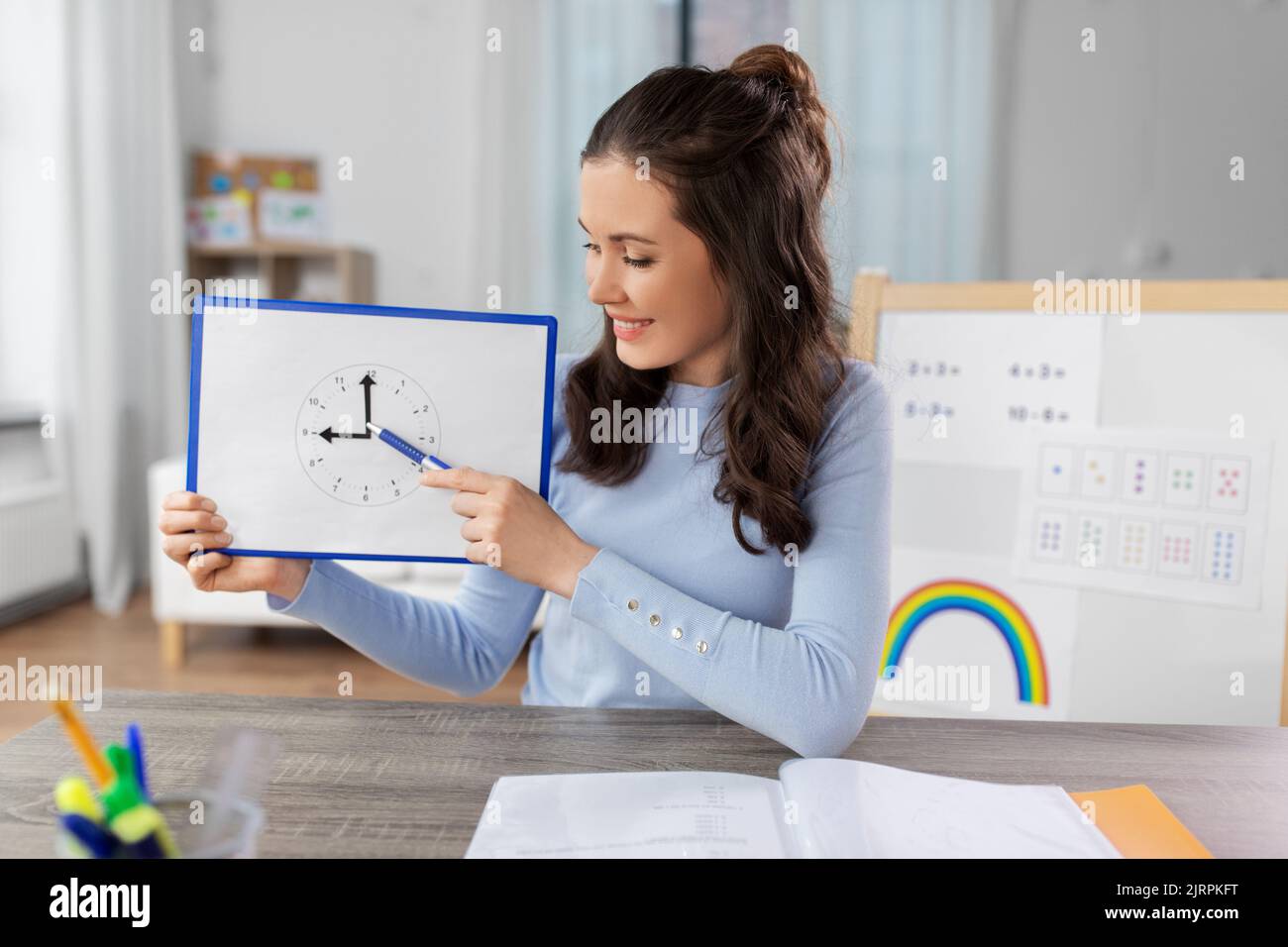 teacher with clock having online class at home Stock Photo
