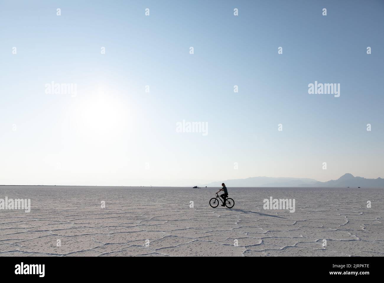 Young woman riding a bike on Bonneville Salt Flats in Utah Stock Photo