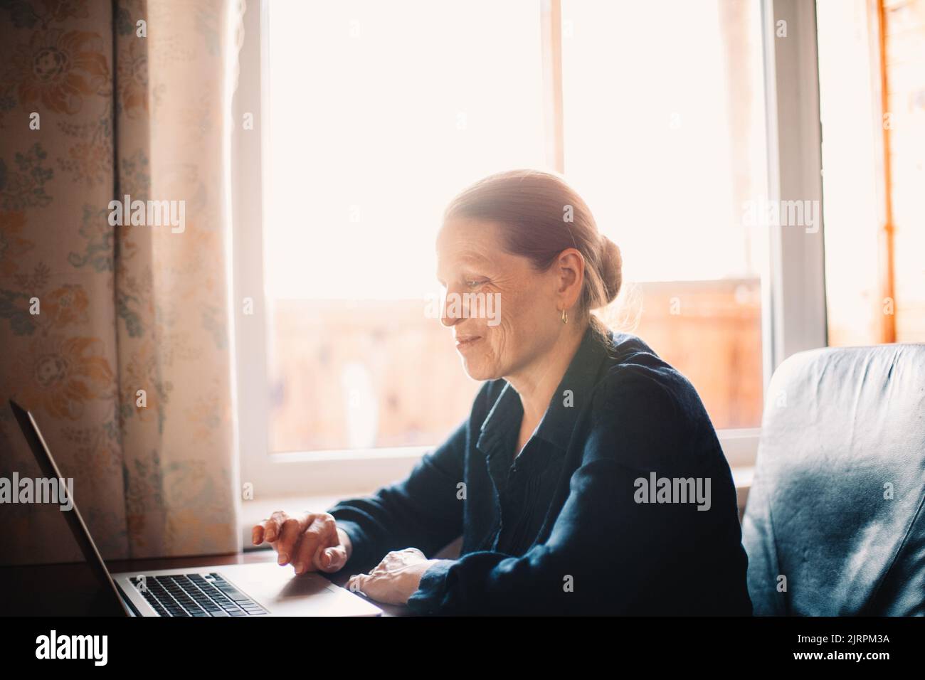 Happy smiling mature woman using laptop computer while working at home Stock Photo