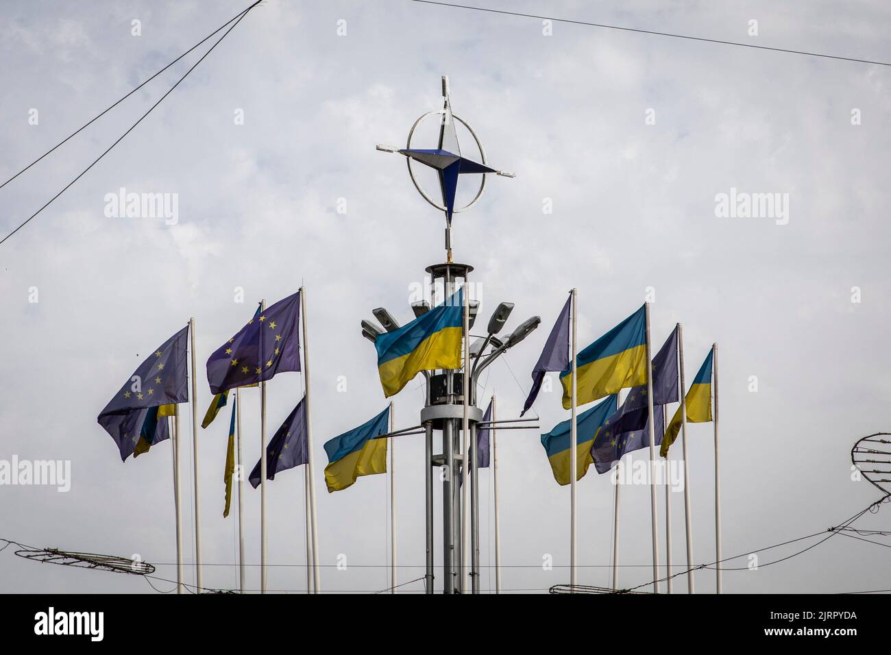 Kyiv, Ukraine. 23rd Aug, 2022. Ukraine's national flags and EU flags are seen under the NATO logo in Kyiv. As dedicated to the upcoming Independence Day of Ukraine, and nearly 6 months after the full-scale invasion of Ukraine on February 24, the country's capital Kyiv held an exhibition on the main street of Khreschaytk Street showing multiple destroyed military equipment, tanks and weapons from The Armed Forces of The Russian Federation (AFRF).As the Russian full invasion of Ukraine started on February 24, the war has killed numerous civilians and soldiers, nearly 9000 Ukrainian military p Stock Photo