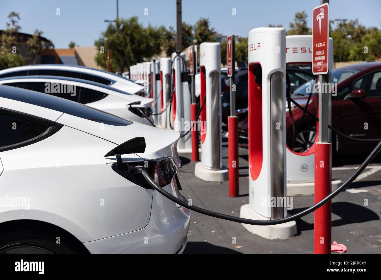 Tesla vehicles and other electric cars are seen charging at a station