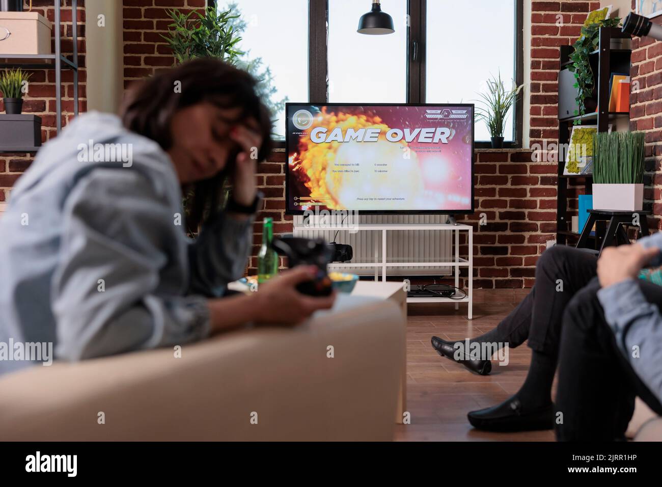 Competitive woman losing after playing shooter video games, feeling frustrated about lost competition. Sad angry person using gaming console to play shooting game, strategy lose. Stock Photo