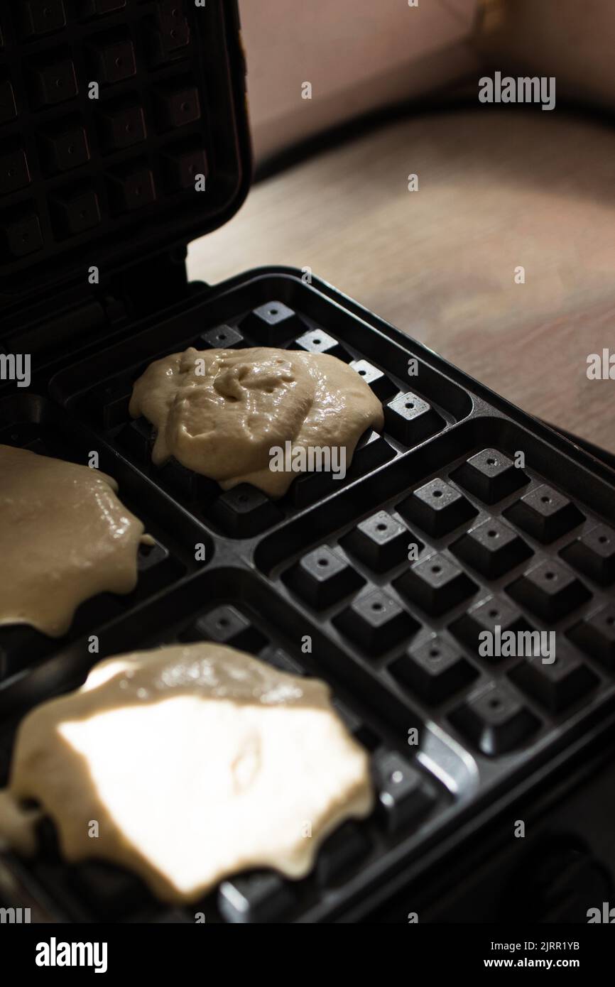 cooking Belgian waffles in a waffle iron. Pour in the dough.. Stock Photo